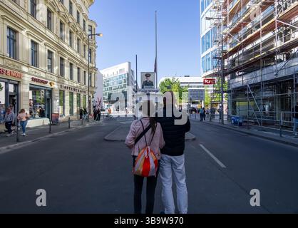 Deux touristes se tiennent au poste-frontière historique Checkpoint Charlie à Berlin, face au panneau de contrôle de l'armée américaine. Banque D'Images