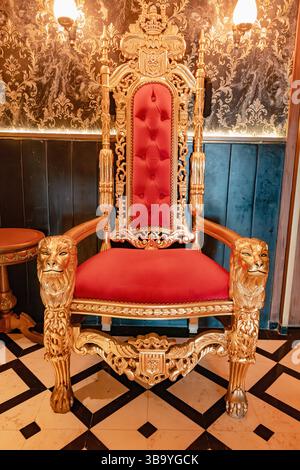 04 mars 2025, Casablanca, Maroc : trône doré orné avec sellerie de velours rouge et détails de tête de lion Banque D'Images