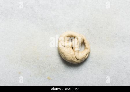 Vue aérienne de la pâte de bretzels maison formée sur un comptoir blanc, vue de dessus de la pâte de bretzels douce sur un fond blanc Banque D'Images