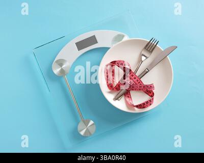 Concept de régime alimentaire. Ruban à mesurer reposant sur la plaque sur une balance numérique placée sur un fond bleu. Banque D'Images
