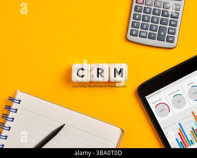 Concept de gestion de la relation client. L'acronyme CRM sur des cubes en bois sur fond jaune de bureau. Banque D'Images