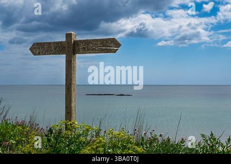 Un panneau en bois altéré indique le chemin vers la plage, Burgh Island, des toilettes, un café et le poste de sauveteur, aidant les visiteurs à naviguer sur la côte Banque D'Images