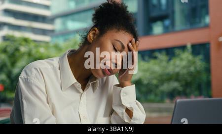Femme afro-américaine femme d'affaires en plein air surtravaillé fatigué épuisé santé malsaine mal de tête mal de tête migraine fille massant temples tête femelle Banque D'Images