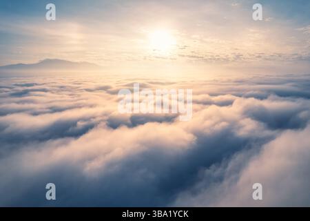 Vue aérienne du lever de soleil doré brille sur la mer de brouillard et montagne lointaine sous le ciel serein Banque D'Images