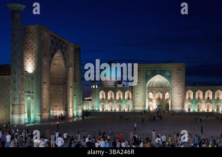 Dôme bleu illuminé à la Madrasa Tilya-Kori et Ulugh Beg Madrasa dans la soirée sur la place du Registan à Samarcande, Ouzbékistan Banque D'Images