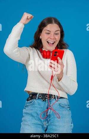 Excité jeune femme célébrant tout en regardant smartphone Banque D'Images
