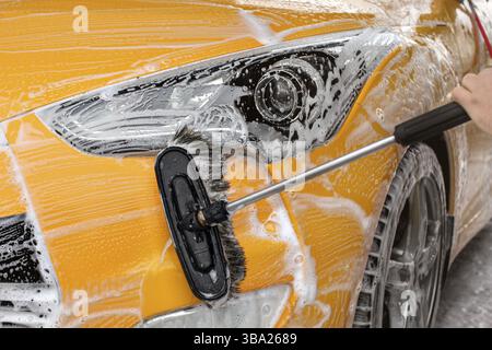 Pare-chocs avant et lumière d'une voiture jaune lavée en self-service, brosse laissant des traits blancs, Liptovsky Mikulas, Slovaquie, Europe Banque D'Images