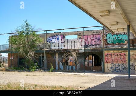 Barstow, Californie, États-Unis. 7 mai 2025. En face de l'ancien restaurant Hacienda Tequila à Barstow, cette structure en ruine servait autrefois de motel combo'''' en bord de route, de station-service en partie, et peut-être un restaurant ou un salon niché derrière les portes arborées. Le squelette de la canopée de combustible s'étend toujours sur un sol aride, projetant une longue ombre sur ce qui était autrefois un îlot de service. À l'étage, les restes d'un panneau marqué 'TÉLÉPHONES' offre un dernier écho de l'ère pré-smartphone, lorsque les voyageurs s'arrêtaient ici non seulement pour le carburant, mais pour un endroit pour se reposer, manger et appeler home.Now éviscéré, étiqueté Banque D'Images