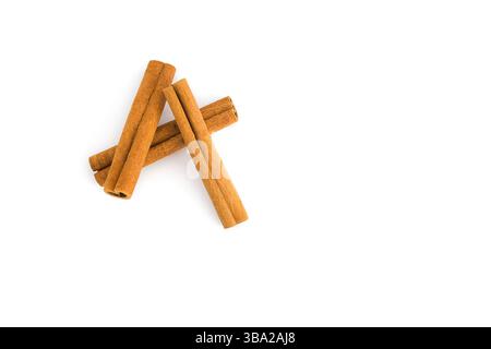 Morceaux d'écorce de cannelle dispersés sur blanc, illustrant les courbes naturelles de l'épice, les surfaces texturées et la riche coloration brune, adapté à la cuisine Banque D'Images