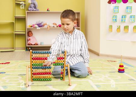 Mignon enfant garçon d'avant-chooler jouant avec la couleur de bois abacus Banque D'Images