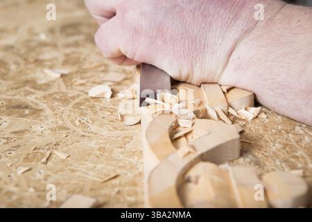 Artisan sculpteur sur bois crée un ornement de meubles. Mains de sculpteur sur bois, ciseaux, outils, ornement sculpté sur bois Banque D'Images