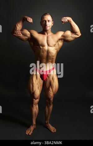 Bodybuilder masculin posant, montrant les muscles du corps avant, tir en studio sur fond noir Banque D'Images
