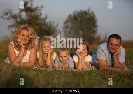 Famille heureuse : mère, père, enfants, fils et filles dans la nature. Une belle famille repose sur l'herbe dans le parc Banque D'Images