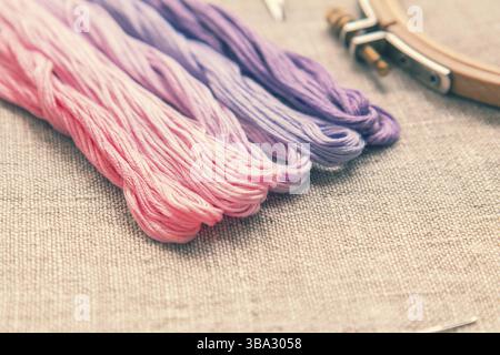 Set pour broderie. Nuances de fil de broderie de couleur violette et rose sur tissu homespun en lin. Coloriage et traitement de photos. Faible profondeur de champ Banque D'Images