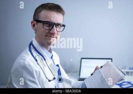 Le sujet de la recherche rapide de maladie cardiaque. Cardiopathie infarctus du myocarde. Médecin analysant l'électrocardiogramme au bureau du cabinet hospitalier. Env Banque D'Images
