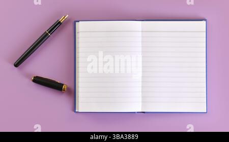 Vue du haut vers le bas - stylo à encre noire avec plume dorée, capuchon ouvert, bloc de papier blanc vide sur panneau lilas près, Liptovsky Hradok, Slovaquie, Europe Banque D'Images
