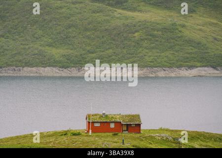 Maison d'été en bois norvégienne (Hytte) donnant sur le lac pittoresque, Norvège, Scandinavie. Chalet au bord du lac en milieu rural. Cabane au toit de tourbe sur le lac. R L'herbe typique Banque D'Images