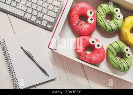 Déjeuner d'affaires en-cas dans le bureau, vue sur le dessus de la boîte à beignets glacés Banque D'Images