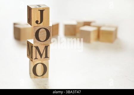 Quatre cubes en bois disposés en pile avec le texte JOMO signifiant joie de manquer sur eux, espace pour l'image de texte en bas à droite, Liptovsky Hradok, SL Banque D'Images
