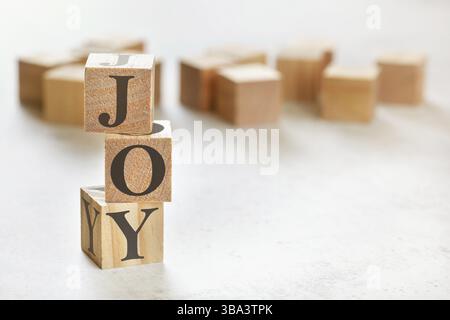 Trois cubes en bois avec le mot JOY, sur la table blanche, plus en arrière-plan, espace pour le texte dans le coin inférieur droit, Liptovsky Hradok, Slovaquie, Europe Banque D'Images