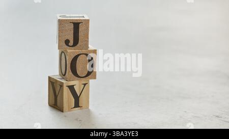 Pile avec trois cubes en bois - lettres JOIE sur eux, espace pour plus de texte / images sur le côté droit, Liptovsky Hradok, Slovaquie, Europe Banque D'Images