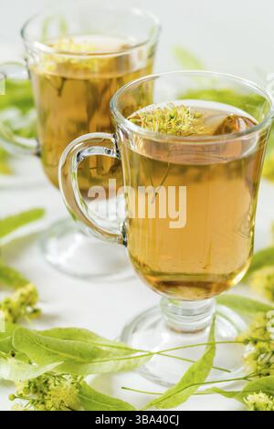 Thé de fleurs de tilleul dans un verre transparent avec un grog tilleul sur la surface en bois blanc Banque D'Images