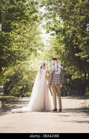 Mariée embrasse joyeuse mariée coucher de soleil temps ensoleillé. Heureux jeunes mariés debout ensemble dans le jardin. portrait de mariage à thème et beau mariage wh Banque D'Images