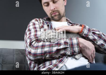 Les animaux de compagnie adorent le thème. L'homme protège très doucement le sommeil des chiens de race britannique de premier ordre tenant dans les bras et en faisant des courses à la maison. Belle relation entre Banque D'Images