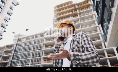 Ingénieur parlant au téléphone. Architecte utilisant le téléphone sur le chantier. Le contremaître du processus de contrôle des appels téléphoniques. Communications des ouvriers de la construction en const Banque D'Images
