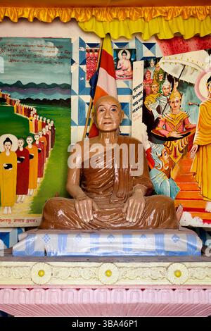 Statue grandeur nature d'un moine vénéré et panneaux muraux narratifs ornent le sanctuaire intérieur de la pagode Chitmorom près de Kaptai, Chittagong Hill Tracts. Banque D'Images