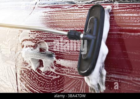 Voiture rouge lavée dans un lave-auto libre-service, détail sur la brosse laissant des traits sur la porte latérale et la poignée, Liptovsky Mikulas, Slovaquie, Europe Banque D'Images