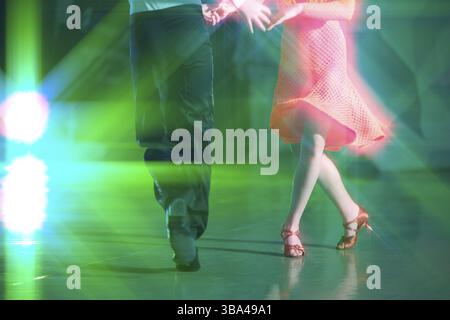 Fond abstrait de danse de salle de bal dans les rayons de l'éclairage de scène. Les jambes des danseurs font des mouvements de danse Banque D'Images