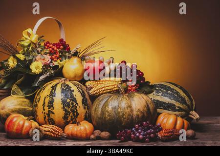 Récolte d'automne de légumes et de fleurs sur la table. La composition des citrouilles, du maïs, des raisins, des poires et des pommes Banque D'Images