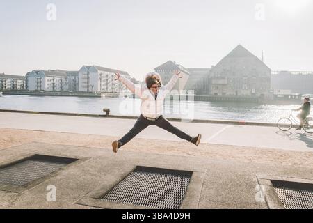 La personne adulte se réjouit comme un enfant. Terrain de jeux trampoline dans le sol, trampoline enfants, sources jette les gens amusant et cool. Copenhague River EMBANK Banque D'Images