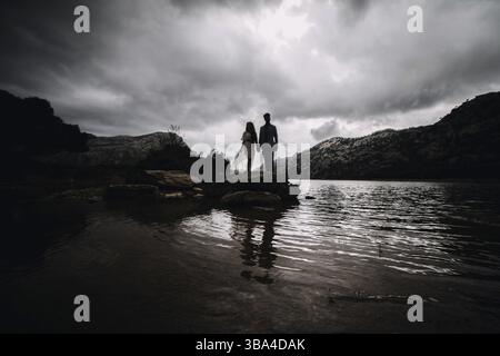 Un couple romantique de jeunes lysés latins debout et embrassant à l'extérieur dans une journée brumeuse dans un plan horizontal pleine longueur. Tramuntana, Majorque Espagne avril 2019 Banque D'Images