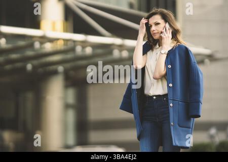 Caucasian business femme parlant au téléphone. Taille portrait d'une femme d'affaires européenne réussie femme, parler au téléphone, debout sur du verre b Banque D'Images