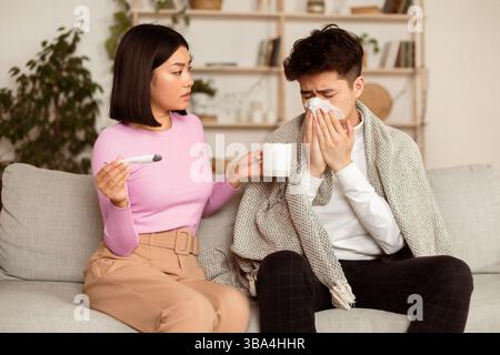 Femme asiatique traitant mari malade lui donnant la médecine à la maison Banque D'Images