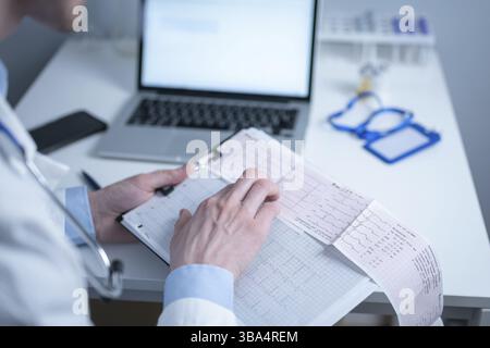 Le sujet de la recherche rapide de maladie cardiaque. Cardiopathie infarctus du myocarde. Médecin analysant l'électrocardiogramme au bureau du cabinet hospitalier. Env Banque D'Images
