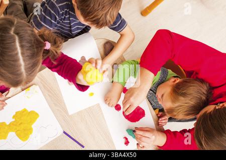 L'enseignant aide le garçon à faire une figure de plasticine sur la table Banque D'Images