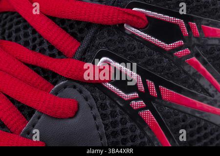 Un fragment d'une sneaker noir avec des lacets rouges close up. La texture de l'espadrille Banque D'Images