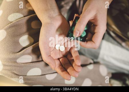 Sous réserve de la santé de la médecine et des produits pharmaceutiques. Macro Close-up young caucasian woman hands sorti une plaquette verte. Deux d'emballage de comprimés en rond blanc Banque D'Images