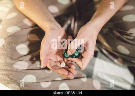Sous réserve de la santé de la médecine et des produits pharmaceutiques. Macro Close-up young caucasian woman hands sorti une plaquette verte. Deux d'emballage de comprimés en rond blanc Banque D'Images