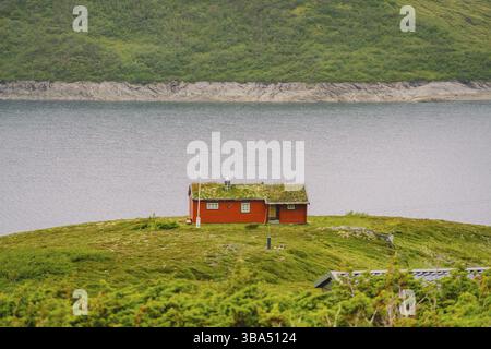 Maison d'été en bois norvégienne (Hytte) donnant sur le lac pittoresque, Norvège, Scandinavie. Chalet au bord du lac en milieu rural. Cabane au toit de tourbe sur le lac. R L'herbe typique Banque D'Images