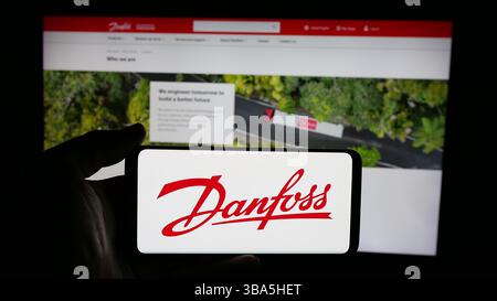 Allemagne. 24 avril 2025. Dans cette illustration photo, une personne tient un téléphone portable avec le logo de la société danoise de chauffage-climatisation Danfoss COMME sur l'écran en face de la page Web. (Crédit image : © timon Schneider/SOPA images via ZUMA Press Wire) USAGE ÉDITORIAL SEULEMENT ! Non destiné à UN USAGE commercial ! Banque D'Images