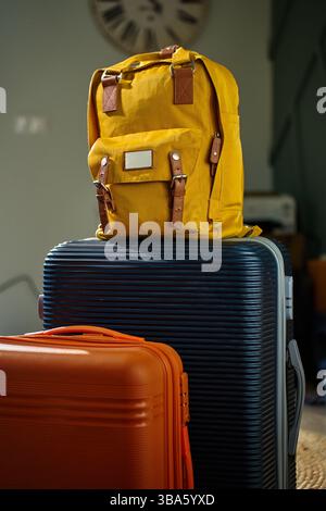 Sac à dos jaune et deux valises prêtes pour le voyage. Bagages emballés dans le salon. Concept de vacances et préparation au départ Banque D'Images