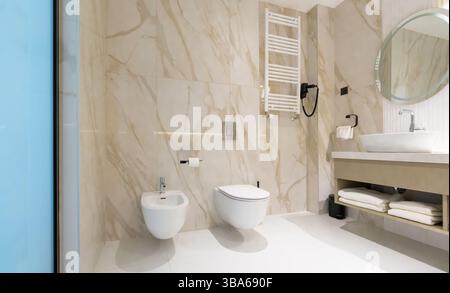 Une salle de bains moderne et propre avec toilettes, bidet et lavabo dans un élégant intérieur en marbre Banque D'Images