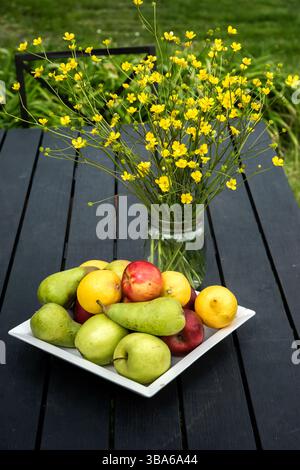 Fruits frais et fleurs sauvages sur une table en bois dans un jardin ensoleillé settingg Banque D'Images