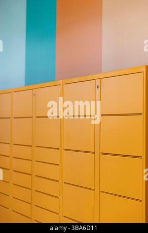 Casiers orange avec des bandes pastel verticales sur le mur - rose bleu Banque D'Images