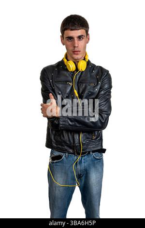 dj élégant avec écouteurs jaunes et veste en cuir noir, posant avec les bras croisés sur fond blanc Banque D'Images