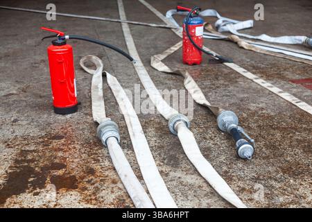 Cylindre d'extincteur rouge avec tuyaux d'incendie déroulés. Banque D'Images